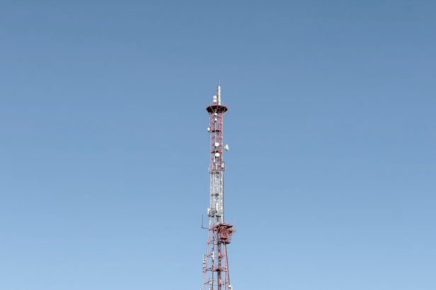 Torre de telecomunicações destacada contra um céu azul, representando a infraestrutura das redes móveis.