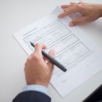 Profissional analisa um formulário de solicitação sobre uma mesa de trabalho.