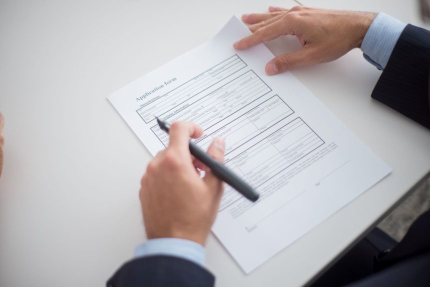 Profissional analisa um formulário de solicitação sobre uma mesa de trabalho.
