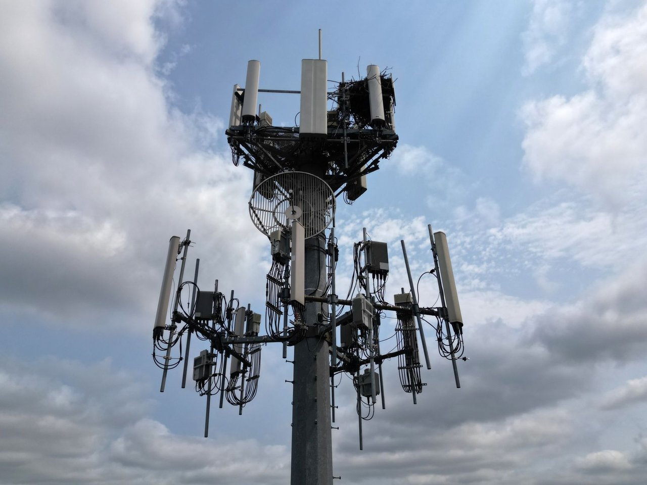Torre de telecomunicações equipada com diversas antenas sob um céu nublado.