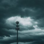 Torre de telefonia celular isolada diante de um céu carregado de nuvens de tempestade.