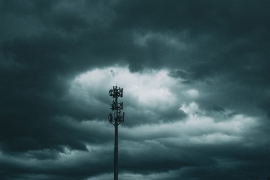 Torre de telefonia celular isolada diante de um céu carregado de nuvens de tempestade.