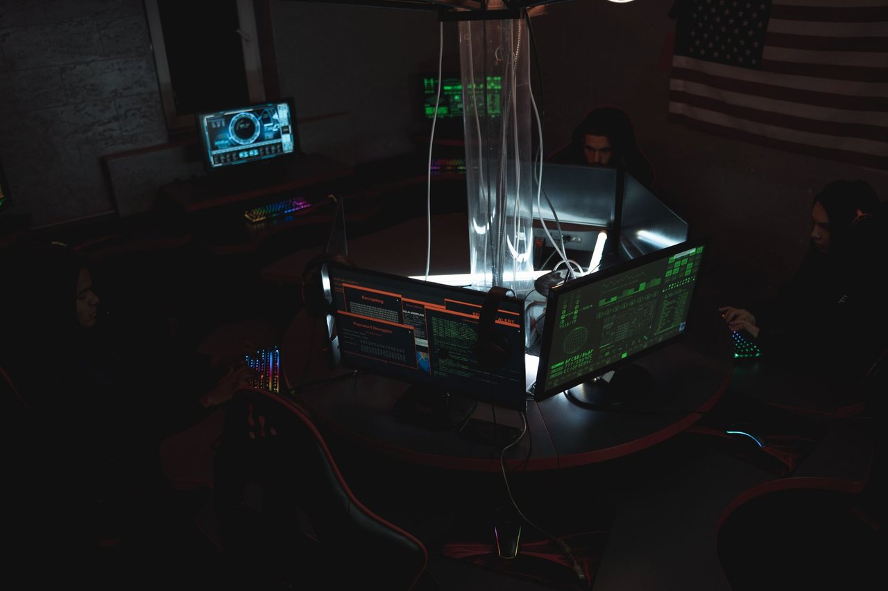 Equipe de especialistas em cibersegurança trabalhando em conjunto diante de computadores em uma sala escura