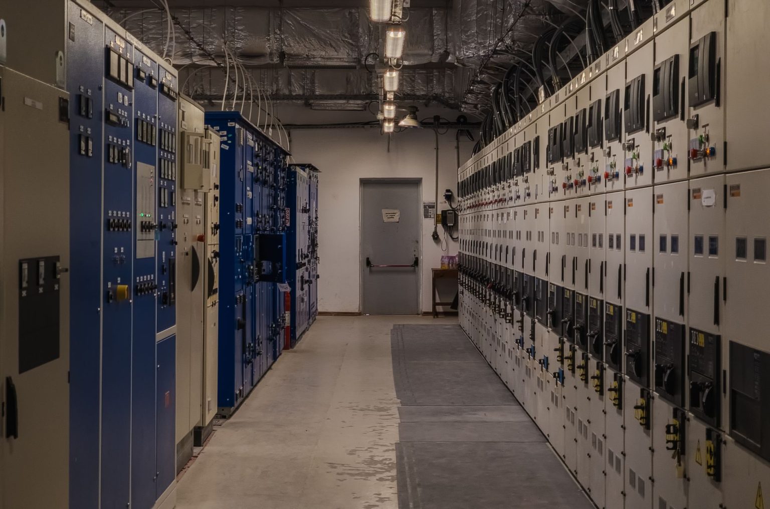 Sala de controle industrial com painéis elétricos e equipamentos de monitoramento.