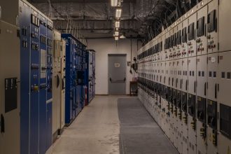 Sala de controle industrial com painéis elétricos e equipamentos de monitoramento.