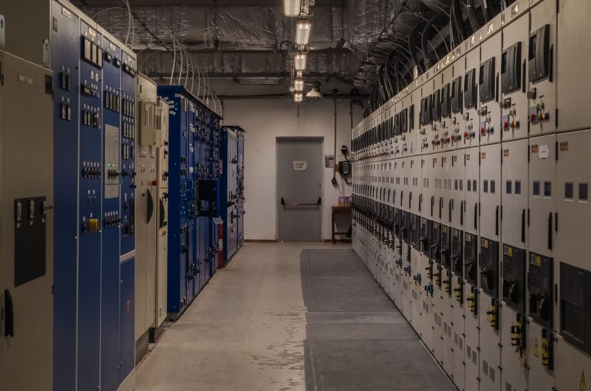 Sala de controle industrial com painéis elétricos e equipamentos de monitoramento.