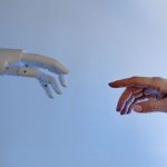 Mão humana estendida em direção a uma mão robótica, simbolizando a interação entre pessoas e inteligência artificial.